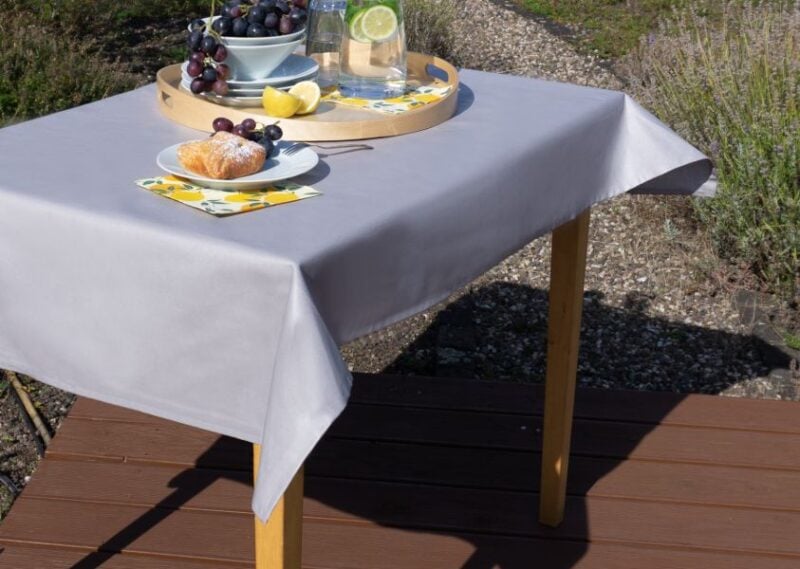 Filigrane Tischdecke in Graphitfarbe, aus hochwertigem Textil, elegant drapiert auf einem Holztisch.