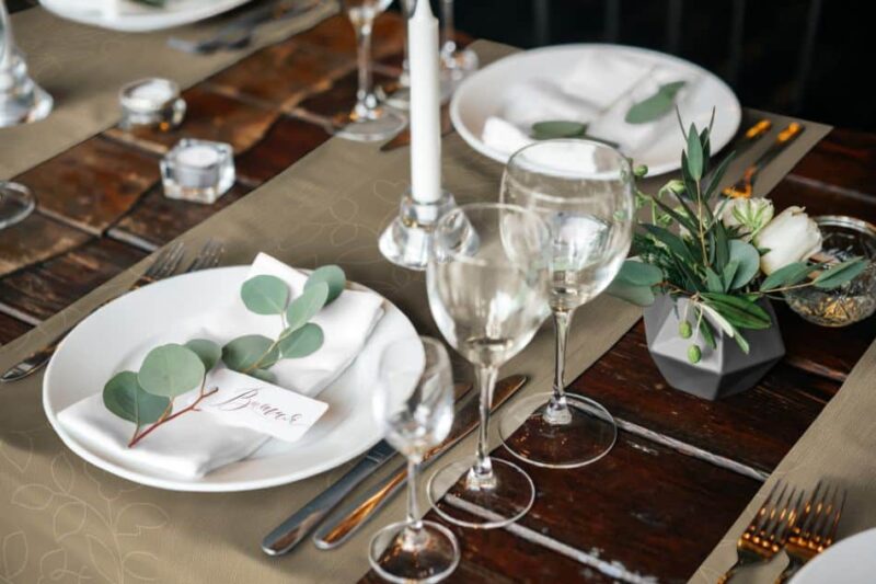 Elegante Tischdecke in Braun mit floralen Elementen, gedeckt mit Geschirr, Gläsern und einer Blumendekoration.