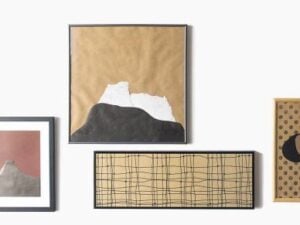 Verschiedene Bilderrahmen mit abstrakten Kunstwerken in neutralen Farben an einer Wand.