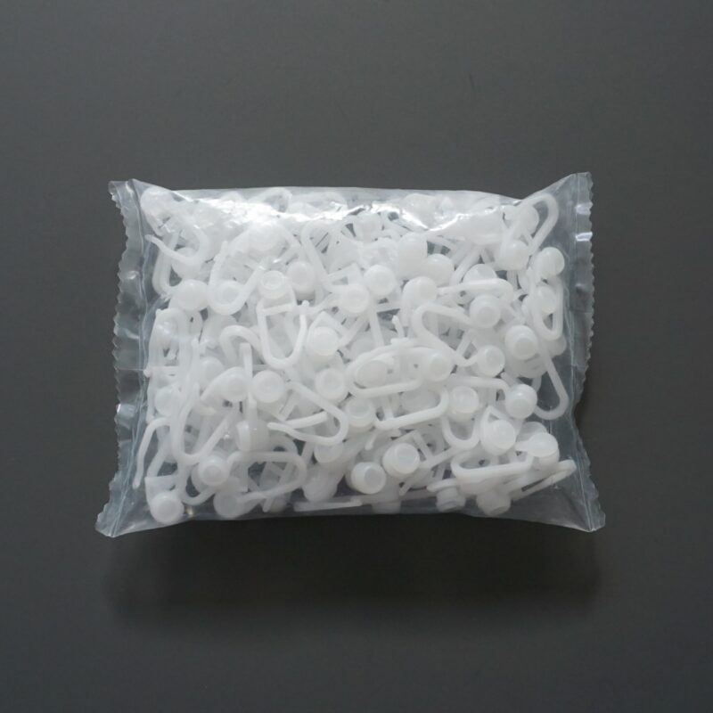 Eine durchsichtige Verpackung mit vielen weißen Gardinenröllchen aus Kunststoff.
