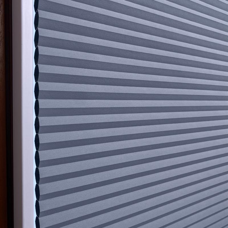 Hochwertiges, graublaues Wabenplissee mit strukturierten, horizontalen Linien für effektiven Lichtschutz.