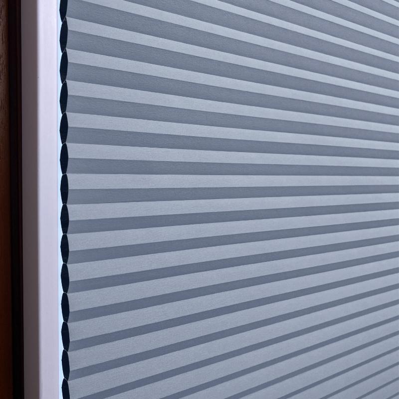 Helle, kreideblaue Wabenplissee-Jalousie mit horizontalen Falten, ideal für Verdunkelung.