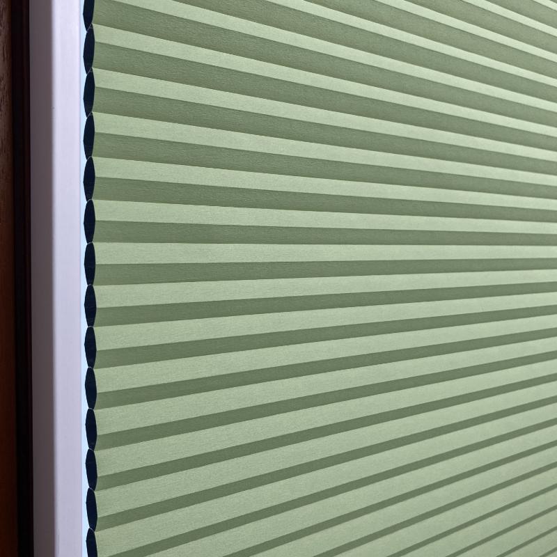 Wabenplissee in Mintgrün mit strukturiertem Design und abgedunkelndem Effekt, seitliche Ansicht.