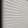 Blickdichtes Plissee in Perlgrau mit horizontalen Falten und transparenten Schnüren. Ideal für Fensterdekoration.