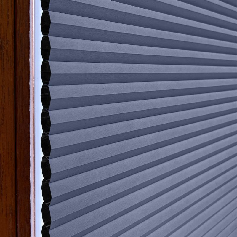 Helle graublaue Wabenplissee-Jalousie mit strukturierten Falten, ideal für Lichtregulierung und Sichtschutz.