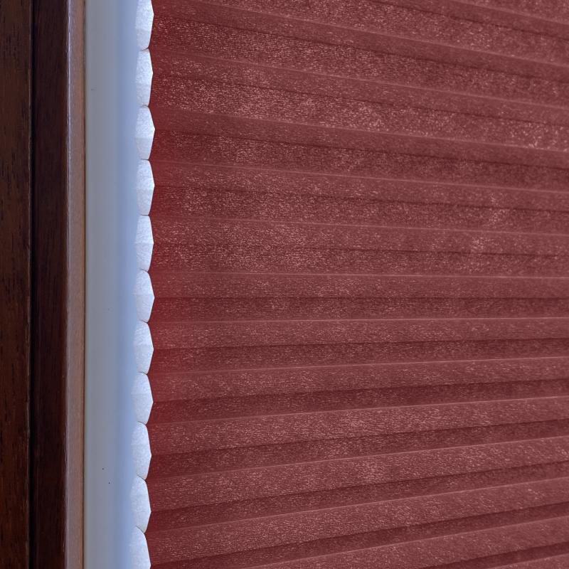 Blickdichtes Wabenplissee in Rubinrot, mit strukturierter Oberfläche und weißem Rahmen. Ideal für Fensterdekoration.