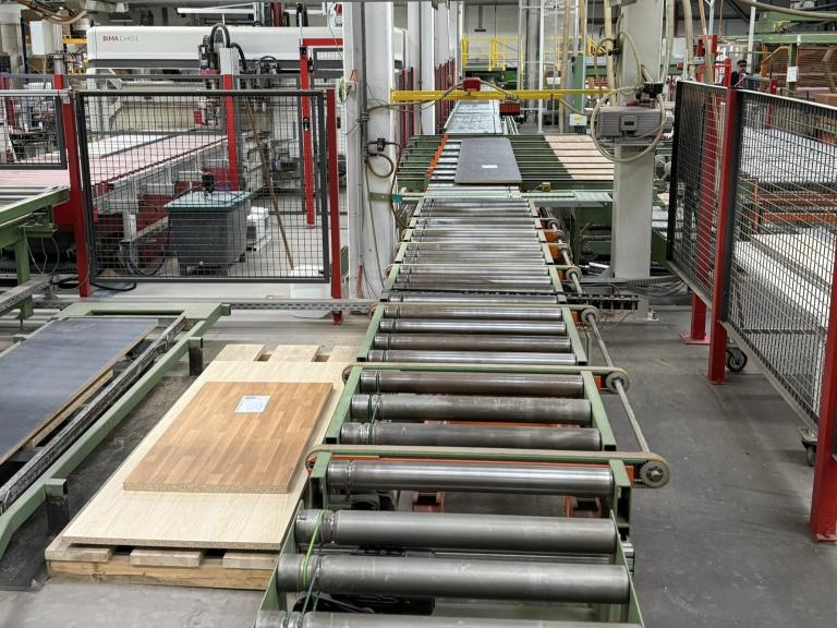 Produktionslinie mit Rollwagen und Holzplatten in einer Fertigungsanlage