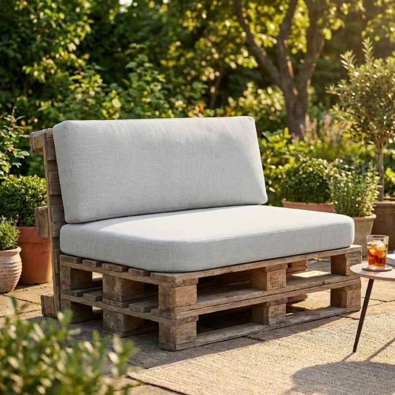 Sofa aus Europaletten mit grauen Sitz- und Rückenpolstern im Outdoor-Bereich.